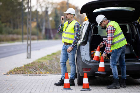 Two builders preparing the road for closing with traffic conesの写真素材