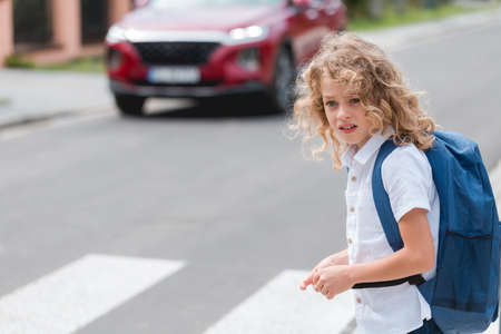 Cute little boy with a blue backpack crosses the streetの写真素材