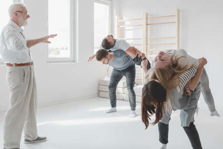 Young people doing spine mobilization with partner during therapyの写真素材