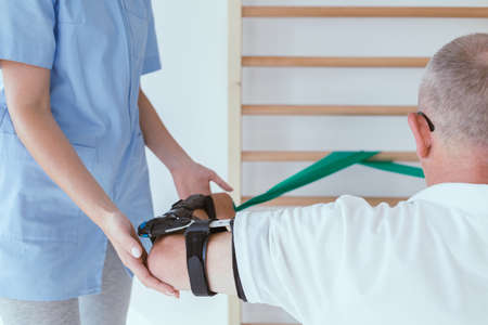 Elderly man doing gymnastic exercises with a young female physiotherapistの写真素材