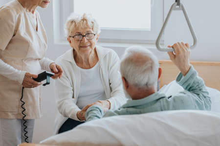 Senior patient gets up from the hospital bed by helping himself with a special handleの写真素材