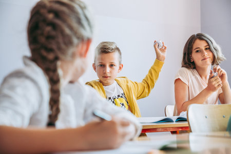 Young boy teasing with a girl during classes throwing a paper ballの写真素材