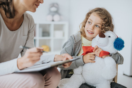 Little boy hugging a teddy bear during therapy with a psychologistの写真素材