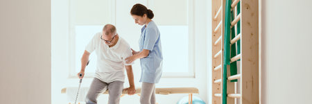 Young physiotherapist exercises in a bright medical office with his injured patientの写真素材