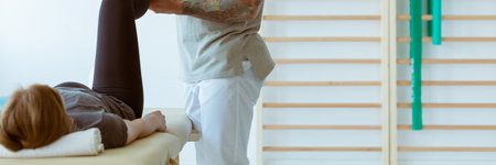 Injured patient and professional physiotherapist doing muscle stretching exercisesの写真素材