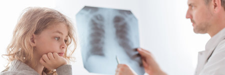 Doctor examining lung's x-ray of cute little child in the hospitalの写真素材