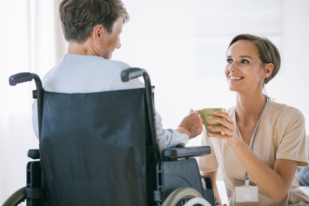 Young supportive nurse helping older woman on a wheelchair in a nursing homeの写真素材