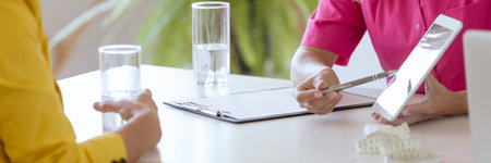 Young nutritionist presenting the food application to her middle-aged patientの写真素材