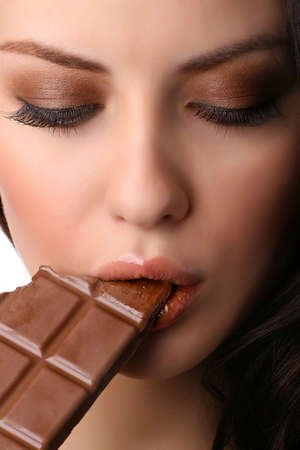 closeup of female face biting a milk chocolate 