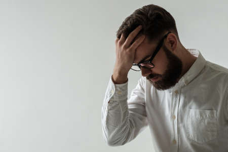 Isolated studio portrait of handsome young adult having a headache and holding hand on foreheadの写真素材