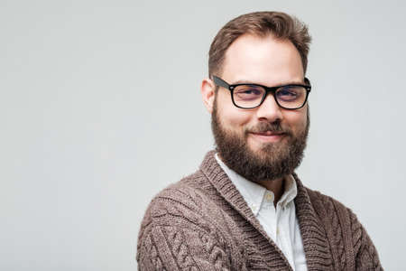 Closeup studio shot of positive young man with beard and glasses isolated on whiteの写真素材