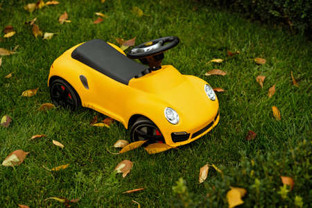 Cool yellow toy car for small child parked on a green grass in garden