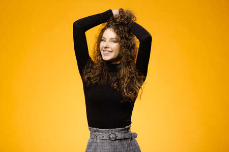 Pretty girl with curly hair isolated on yellow backgroundの写真素材