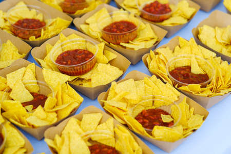 Tasty nachos with ketchup in paper containter. Concept of unhealthy street fast food