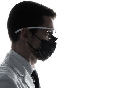 Closeup silhouette portrait of a male dentist wearing dental binocular loupes isolated on whiteの写真素材