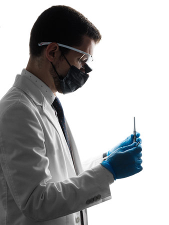 Silhouette of a male dentist wearing magnifying binocular holding medical equipment in handsの写真素材