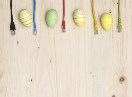 Easter eggs and internet cables on wooden boardの写真素材