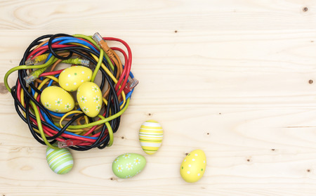 Easter eggs and nest of internet cables on wooden boardの写真素材