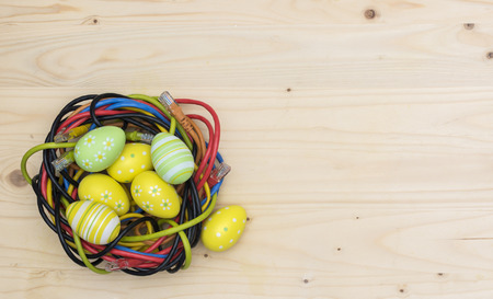 Easter eggs and nest of internet cables on wooden boardの写真素材
