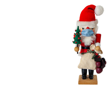 santa claus christmas nutcracker doll holding a tree and bag of gifts and wearing a face maskの写真素材