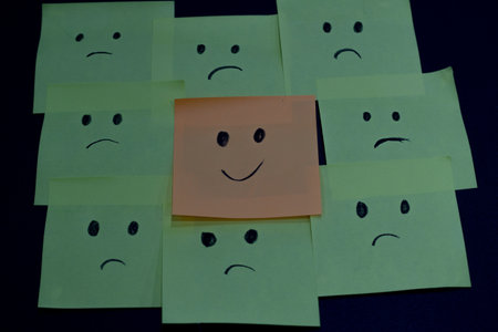 One smiley face amongst all the sad faces drawn on sticky notes.の写真素材