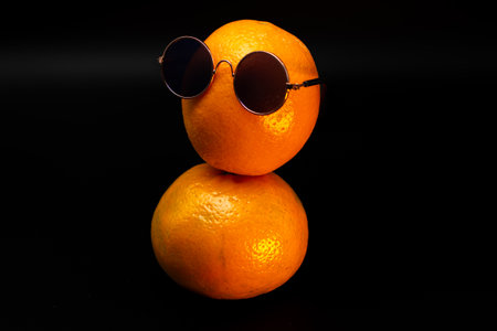 Front view of a orange with sunglasses sitting on top of another orangeの写真素材