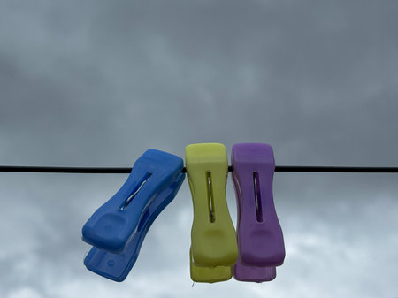 Close up shot of colorful clips hanging on a rope against blue skyの写真素材
