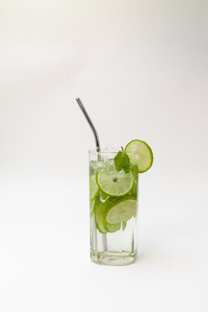 A Glass of detox water with cucumber, lemon, ginger and mint leaves against a white background