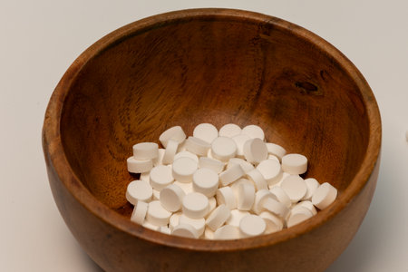 Pills in a wooden bowl on a white backgroundの写真素材