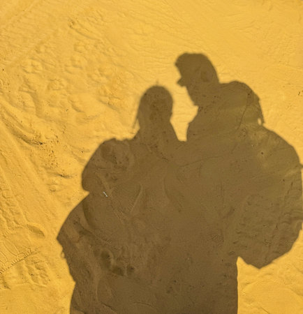 Shadow of a couple falling on the sand on a sunny dayの写真素材
