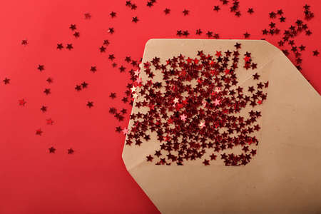 Envelope from craft paper on the red background with glitter shiny stars.の写真素材