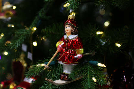 Christmas toy on the spruce branch.Girl skiing in a red dress.Festive concept.Bright lights on the...