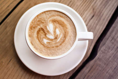 Art cappuccino in the cup on the wooden surface.の写真素材