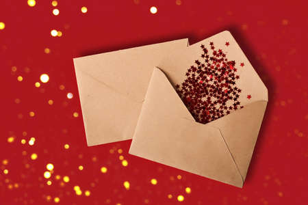 Envelope from the craft paper on the red background with glitter shiny stars.Festive bokh on the...