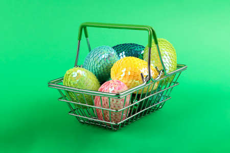 Colorful glossy easter eggs with sequins.Vivid colors.A group of eggs lying in the shopping basket.の写真素材