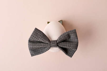 Easter egg with bow tie and ears from natural laves on the trendy pastel background. Minimal...