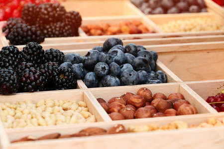 Assorted berries and nuts on a wooden platter. Blueberries, blackberries, almonds, hazelnuts and...