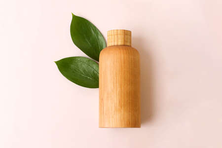 Cosmetics bottle made from wood,on the beige background with fresh,juicy,green leafs.Conept f the natural organic cosmetic,copy space for text.の写真素材