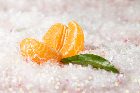 Fresh juicy mandarin with green leaf in the white sparkly snow.Copy space for text.Festive horizontal banner.の写真素材