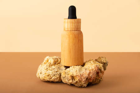 Wooden cosmetics bottle with dropper staying n the decorative natural stones