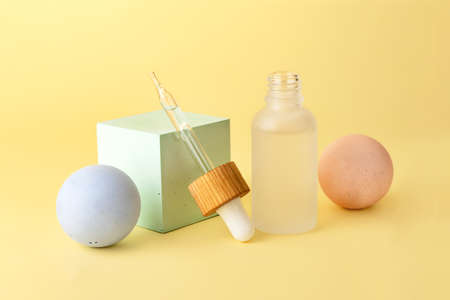 Cosmetics bottle from frosted glass with dropper near.Empty geometrical shape podiums near it - sphere and cube.Good for display products.Pastel colors,minimal concept.Advert banner with copy space.の写真素材