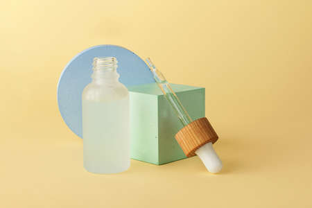 Cosmetics bottle from frosted glass with dropper on the geometric podium.Empty geometrical shape...