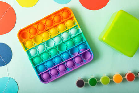 Top view of the new sensory toy - rainbow pop it with children toys on the sides.Antistress toy for...