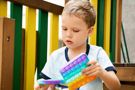 Child playing with two new silicone popping toy on the playground.New sensory antistress toy for children and adult.Trendy rainbow coloring.の写真素材