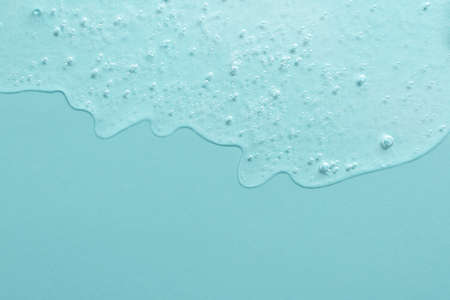 Background from cosmetic gel with bubbles,dripping down.Light blue color,copy space for text or design.Top view,antibacterial liquid surface.Good as background or mockup.の写真素材