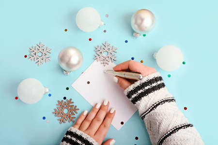 Top view of woman writing on blank greeting card. New year decor around.の写真素材
