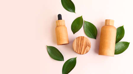 Creative layout from the wooden cosmetics containers with fresh green leafs around.Pretty pastel colors, natural materials.Organic concept.Large banner with copy space.の写真素材