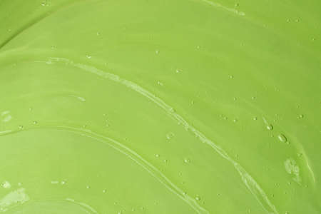 Jelly waved serum with bubbles on the green background.Cosmetics smear of aloe vera or antibacterial...