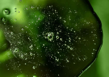 Liquid smear, cosmetics swatch on the green background.Top view, antibacterial liquid surface.Good...