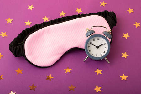 Mask for sleep and alarm clock near it. Circadian rhythms concept.